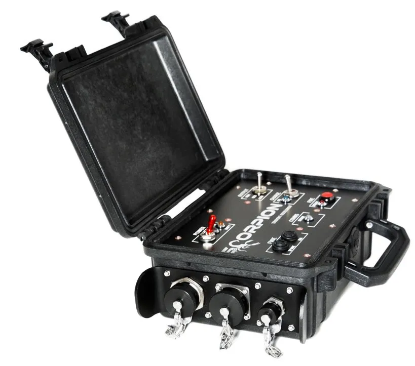A black rugged case seen from the front left, its lid raised, with a black control panel on top carrying the SCORPION name, three toggle switches, one with a red lever, a red button and indicator lights, and three large capped connectors across the front face beside a black carry handle on the right