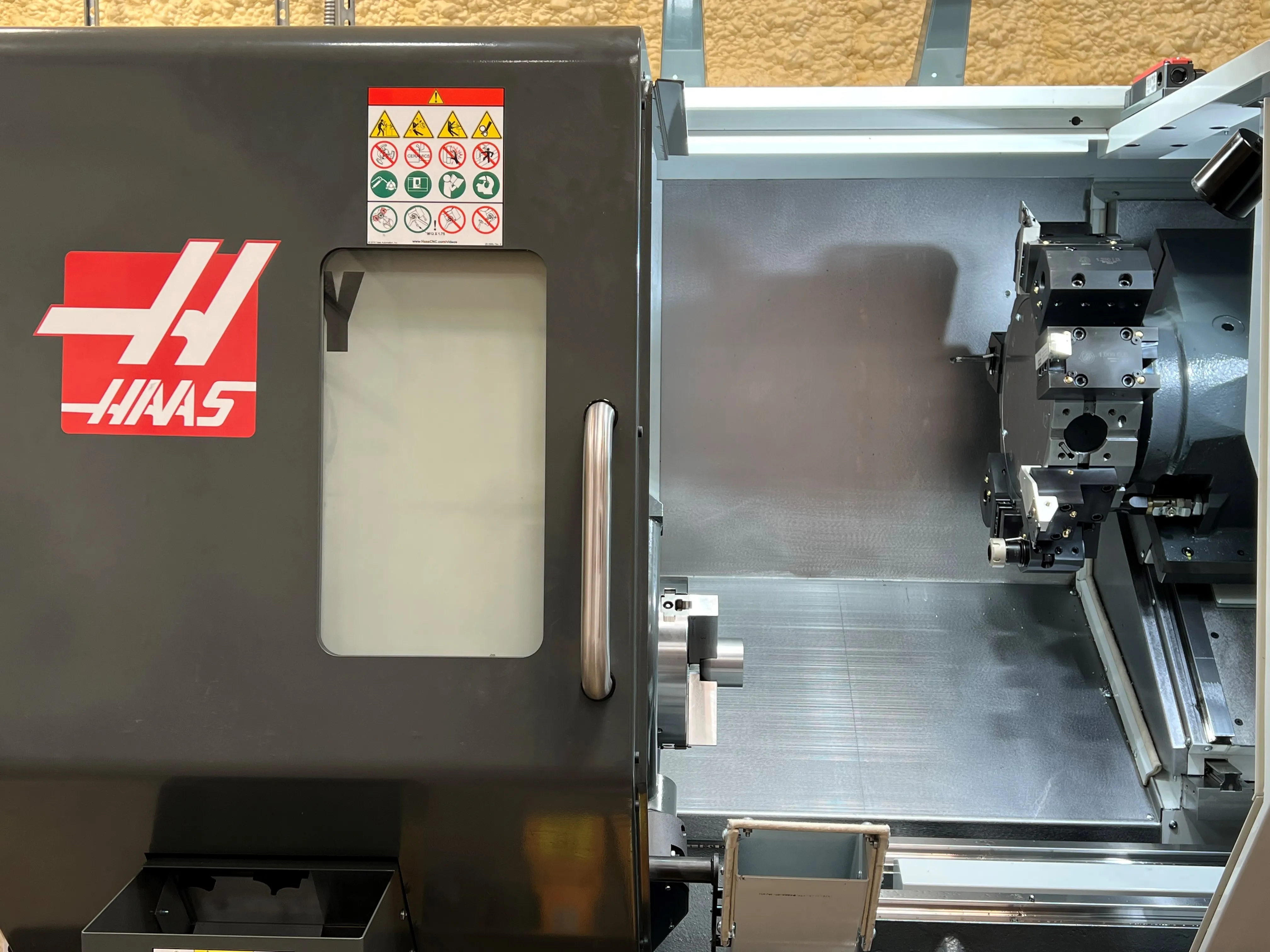 A Haas CNC lathe on the Trident Research shop floor, turret and tooling visible through the open door