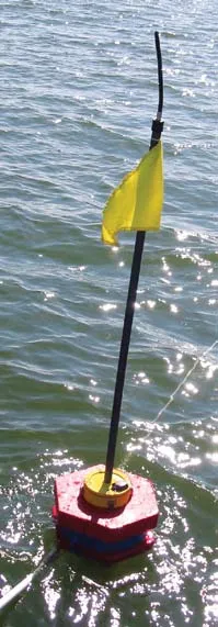 A TARGT sensor float on the water: a red and blue octagonal flotation collar with a yellow cap, a tall black mast and a yellow flag.